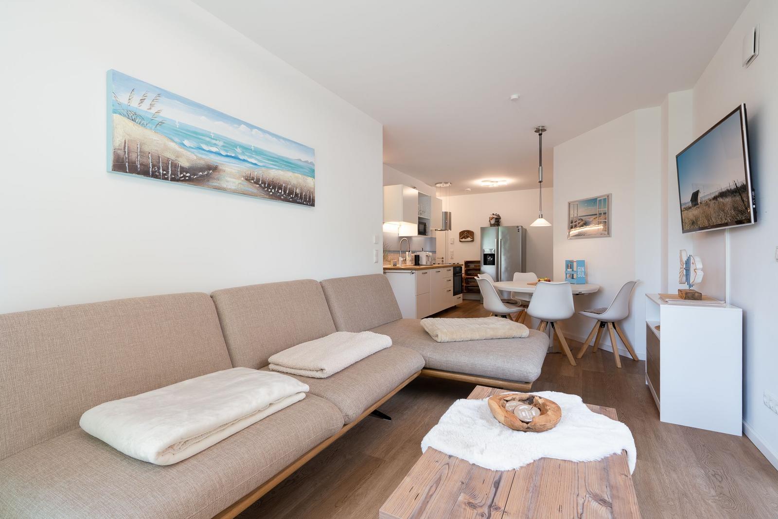 Living area with sofa, coffee table, and kitchen area in the background.