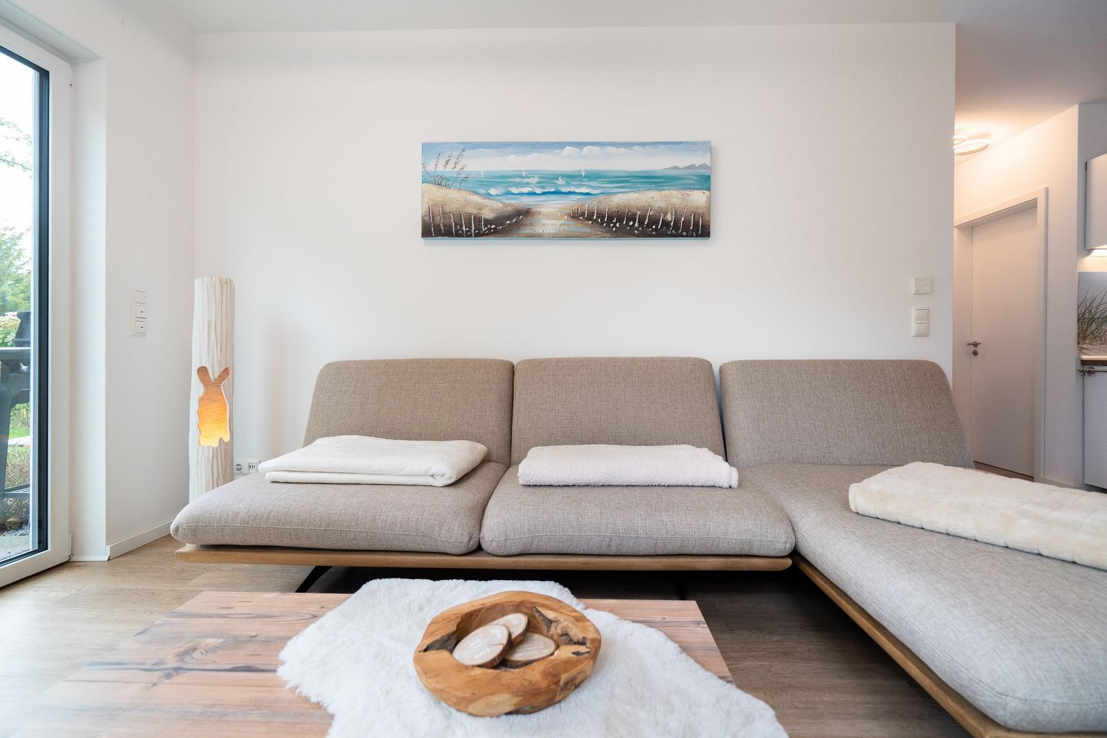 A living room with a light sofa, a wooden table, and a wall painting.