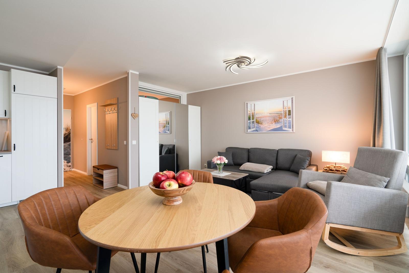 Living and dining area with sofa, chairs, and table. Wall art and lighting visible.