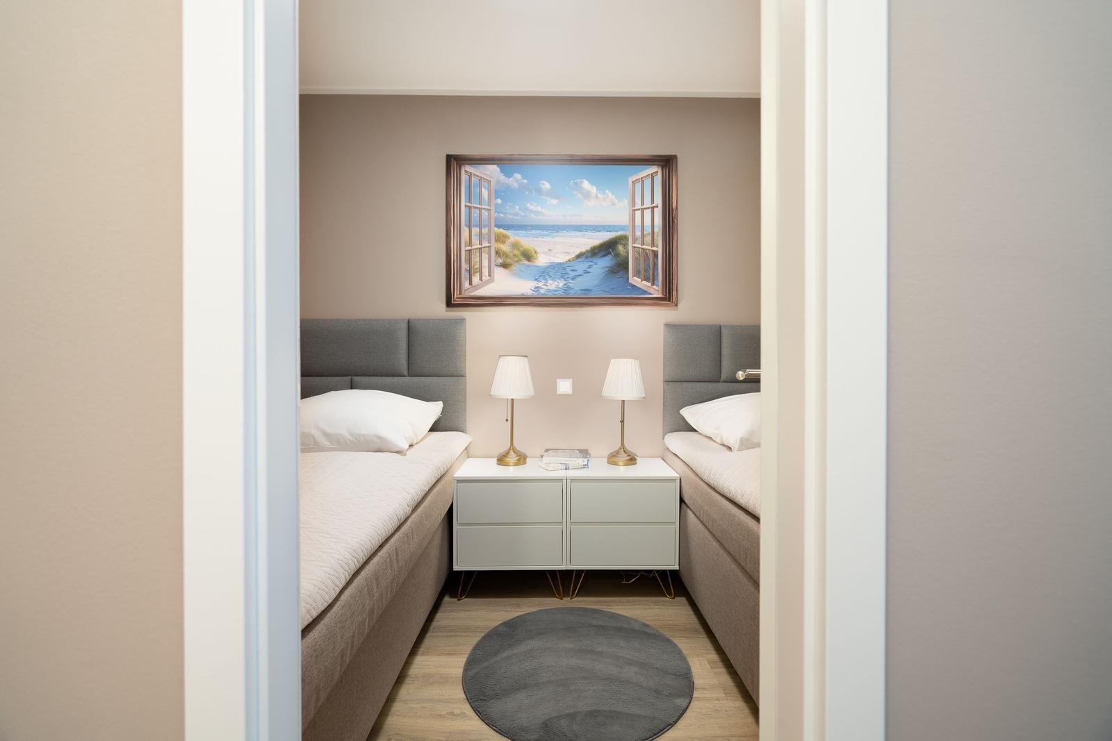Two beds with nightstand and wall mural of a beach.