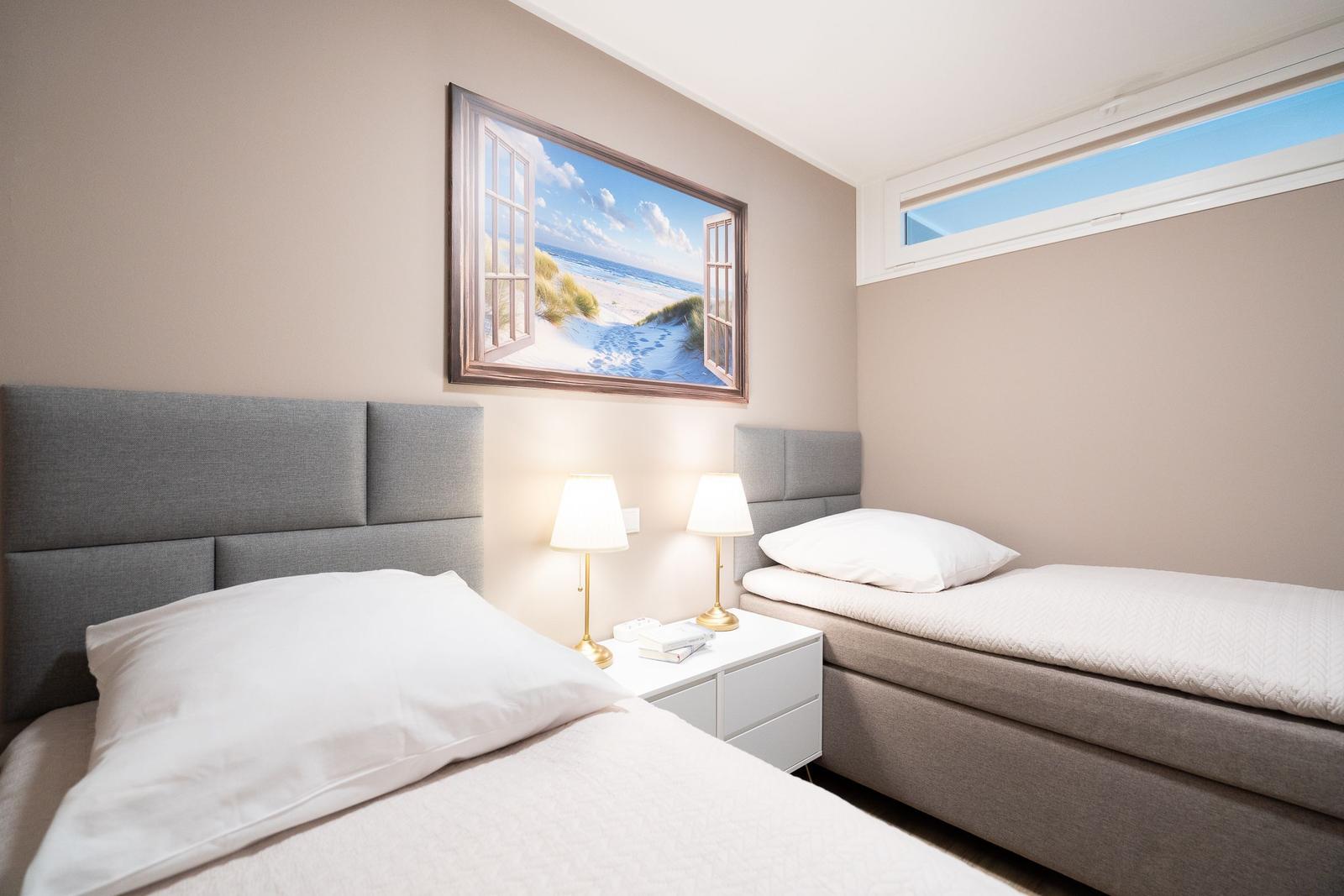 Two beds with headboards, nightstand, and wall picture with beach motif.