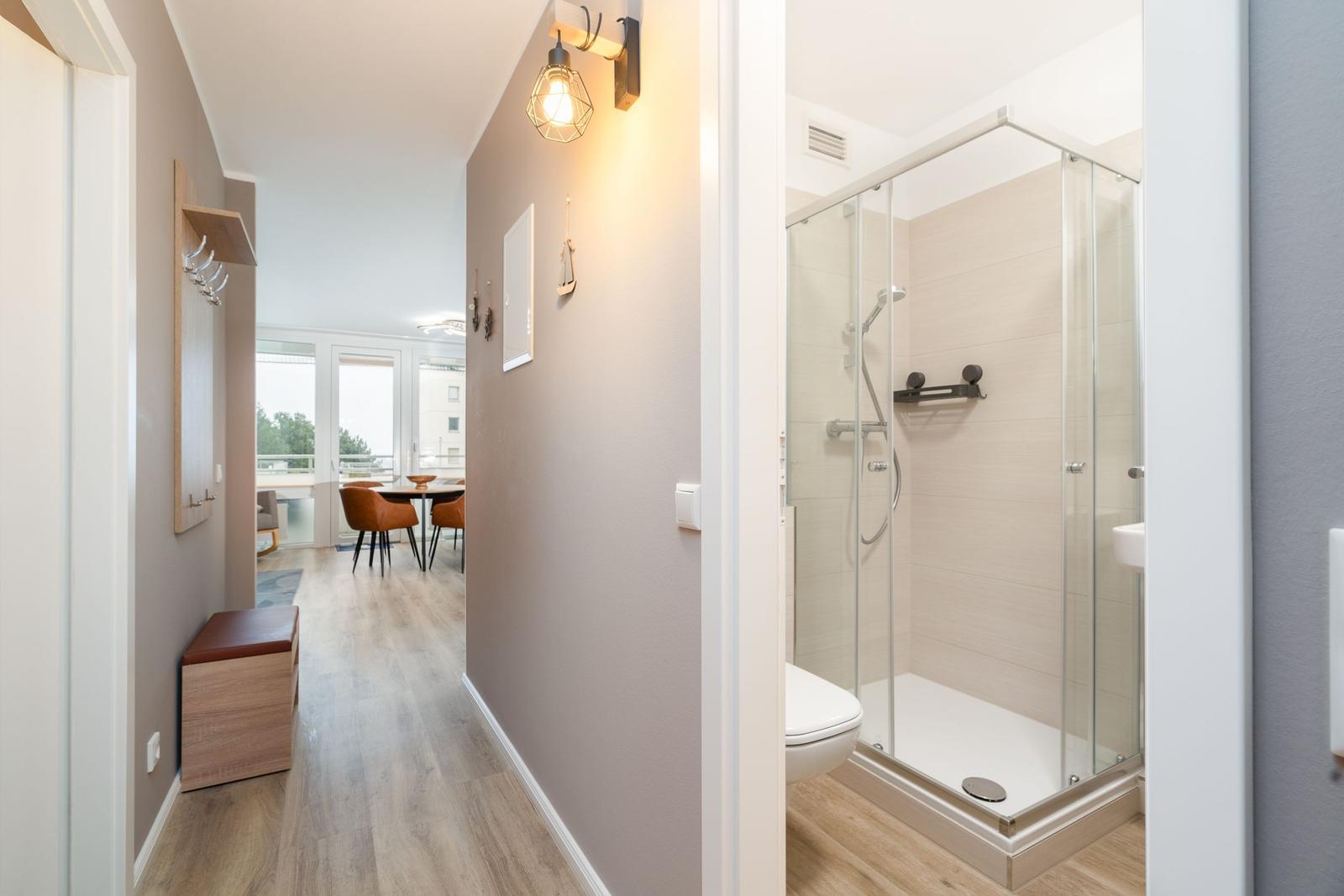 Hallway with bathroom and view into dining area with table and chairs.