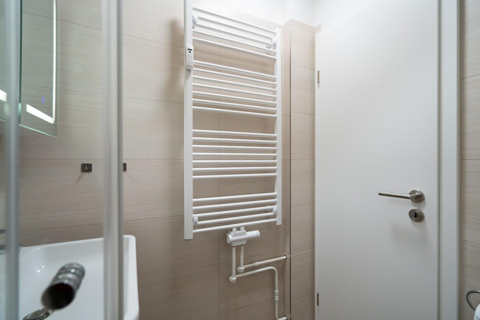 Bathroom with heater, mirror, and shower