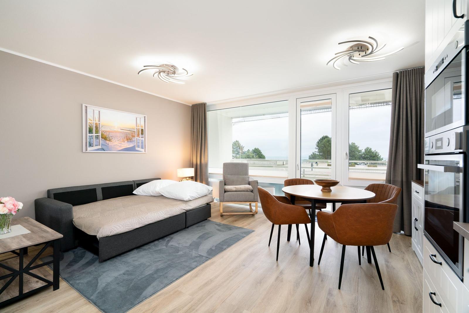 Sleeping area with sofa bed, dining table, and kitchen area with view.