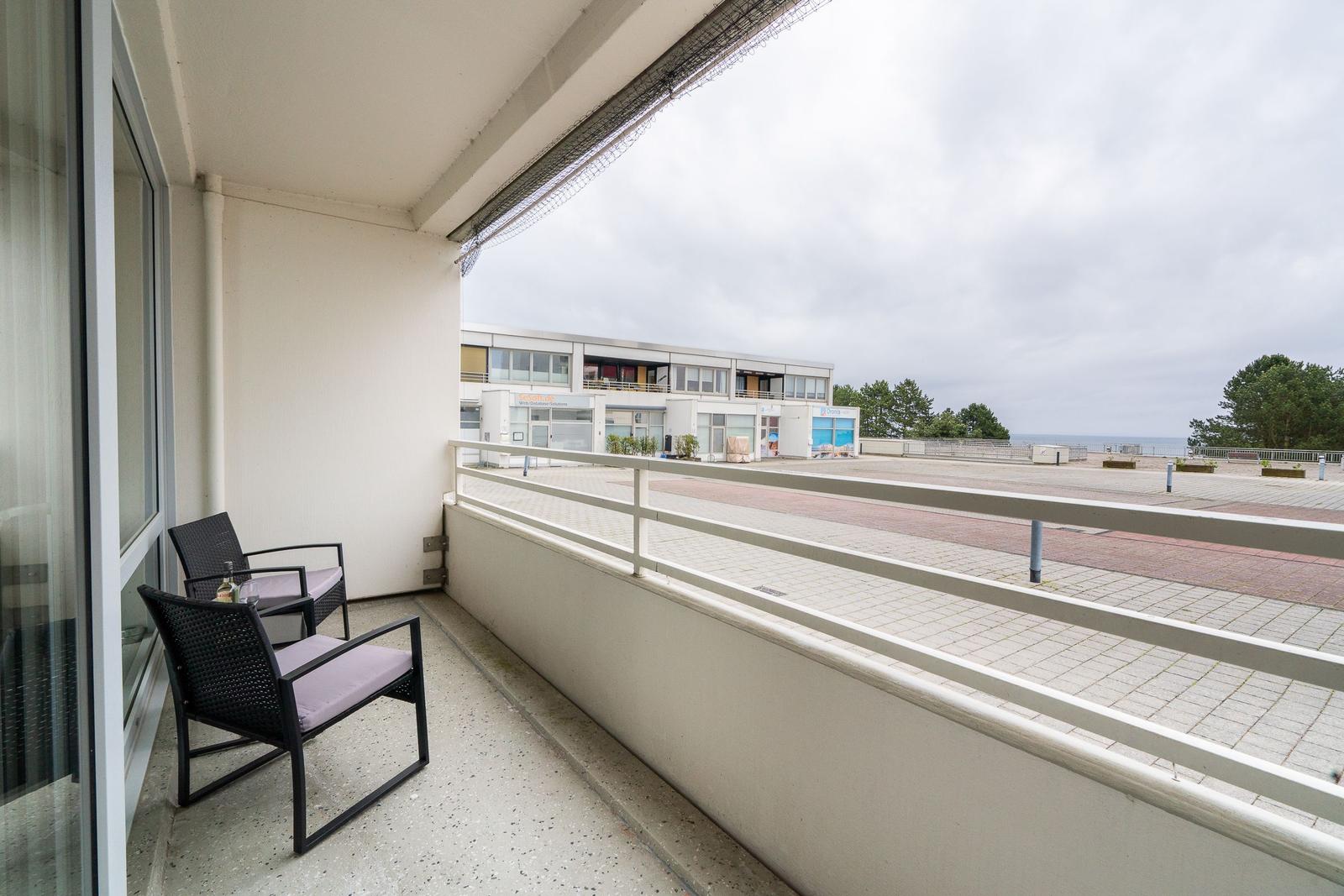 Balcony with two chairs and view of the beach and sea.