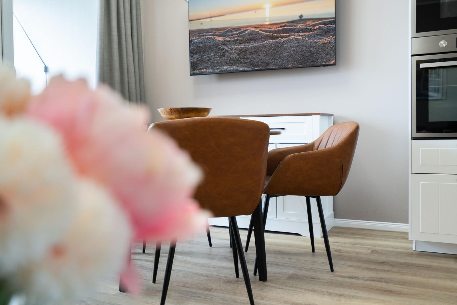 Dining room with brown chairs, white sideboard, and kitchen area.