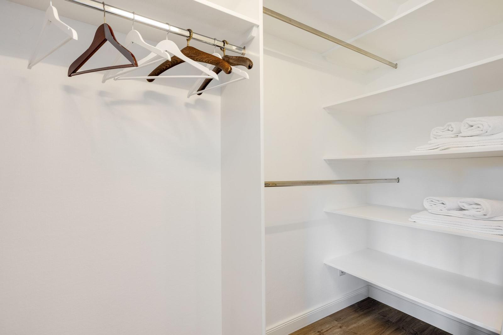 Kleiderständer mit Haken und Regale mit Handtüchern im Schrank.