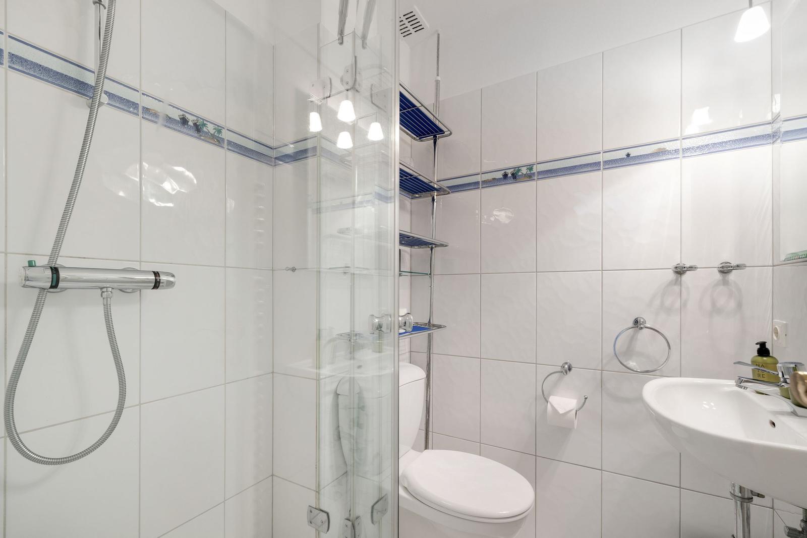 Badezimmer mit Dusche, Toilette und Waschbecken.