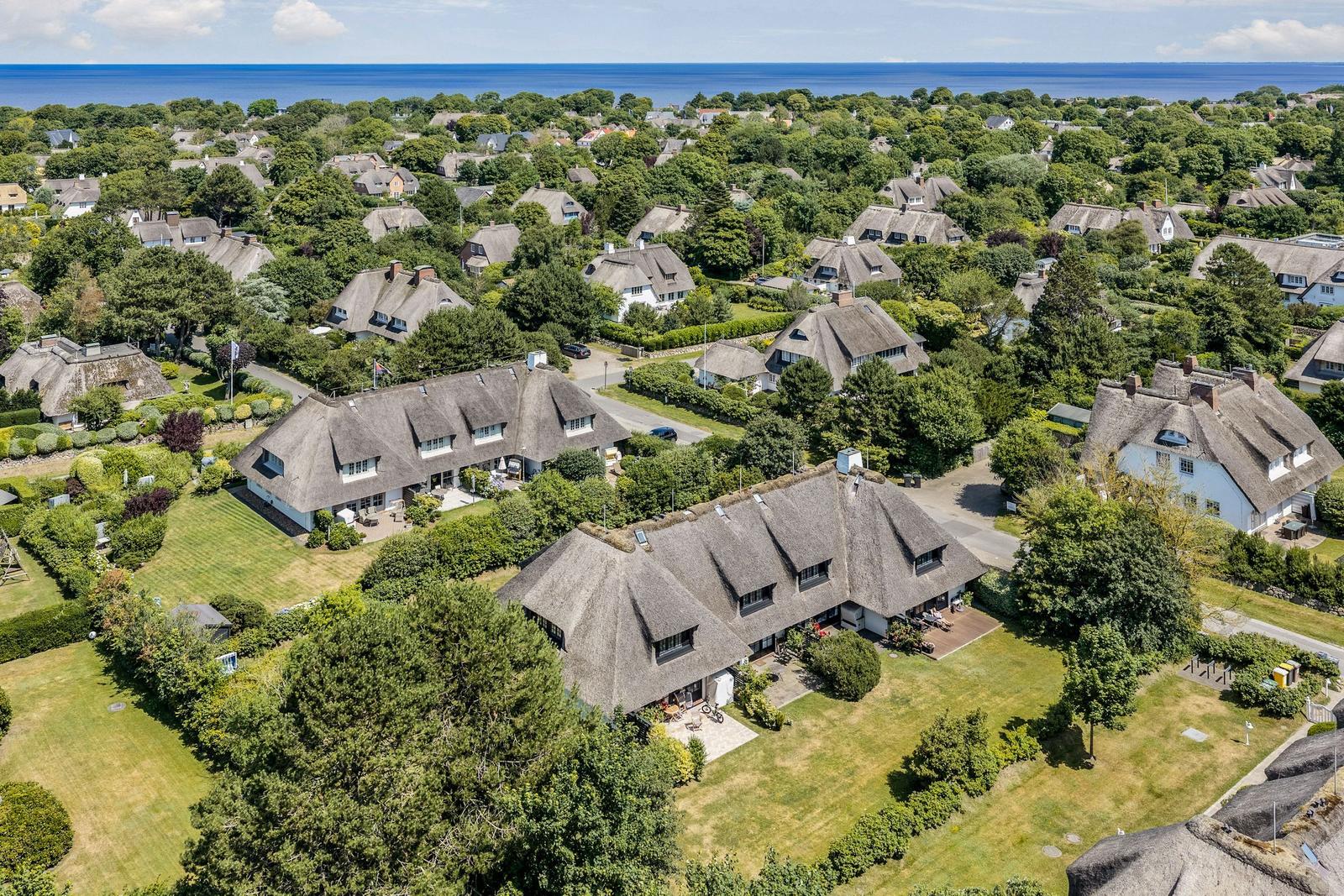 Dorf mit strohgedeckten Häusern und grünen Gärten am Meer