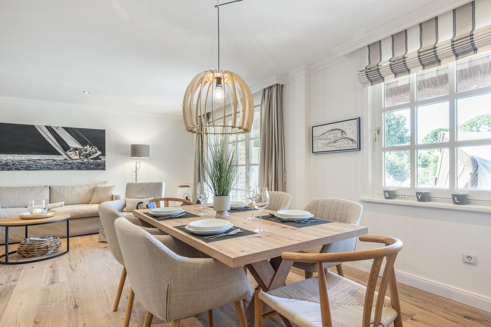 Esszimmer mit Holztisch, Stühlen und Fenster. Wohnbereich mit Sofa und Wandbild.