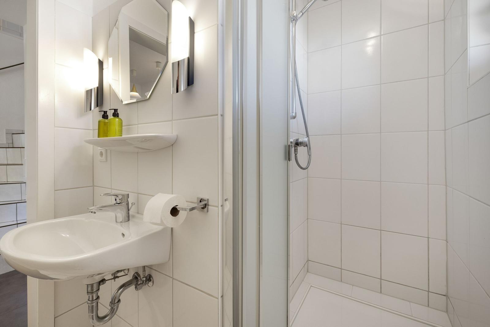 Badezimmer mit Dusche, Waschbecken und Spiegel