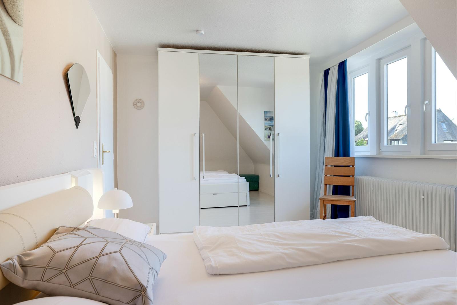 Schlafzimmer mit Bett, Kleiderschrank und Fenster mit Blick.