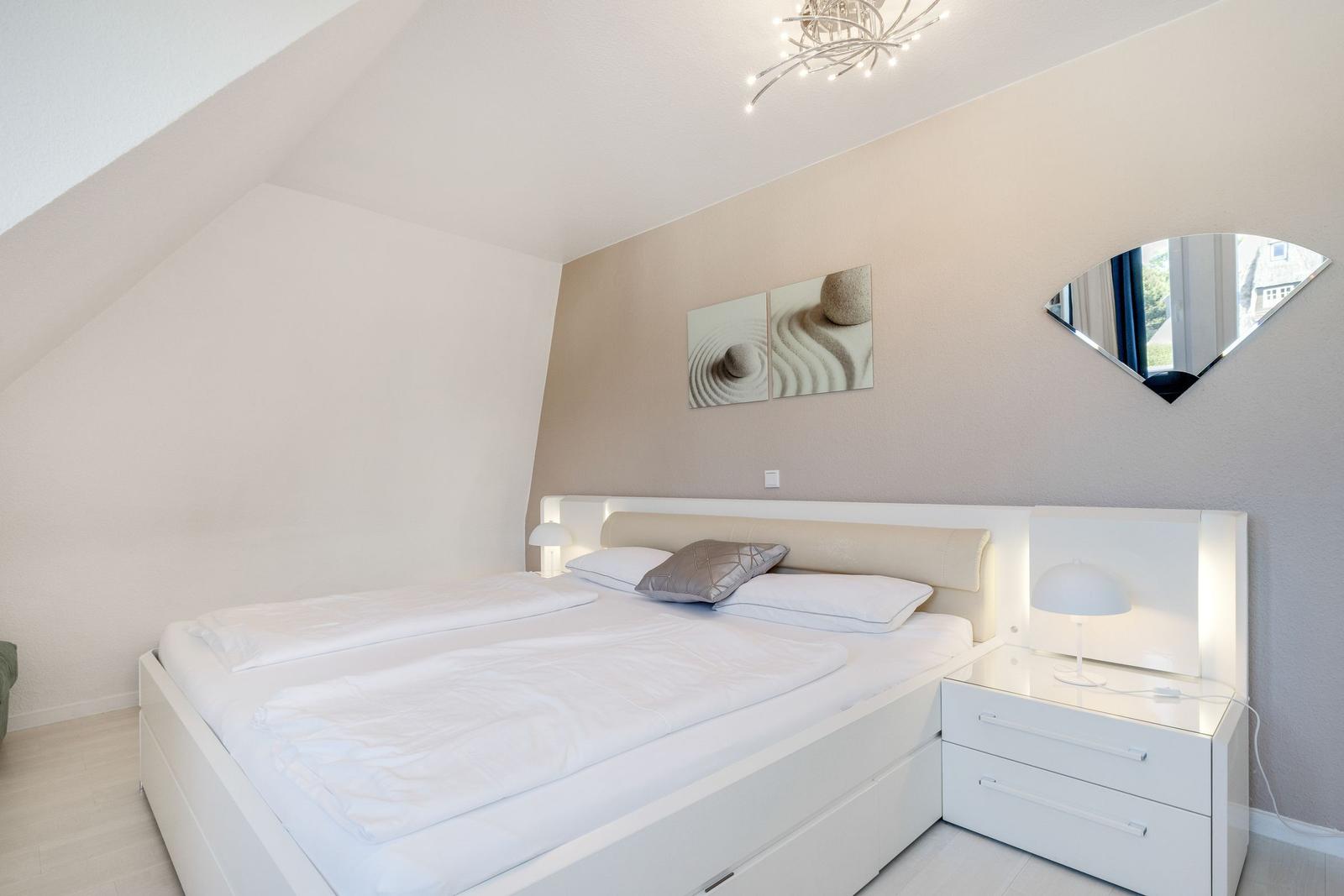 Schlafzimmer mit Doppelbett, Nachttisch und Wandbild.