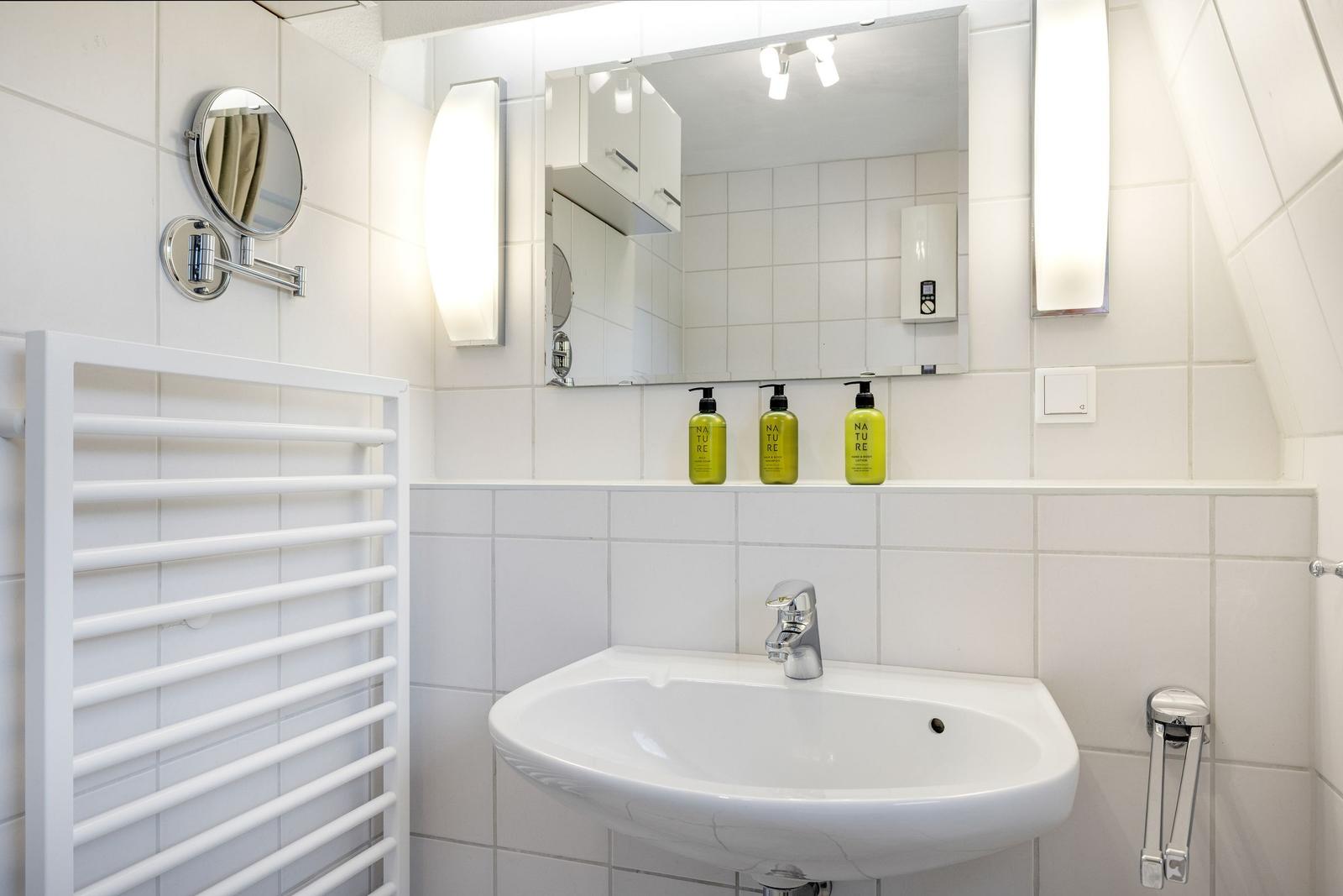 Badezimmer mit Waschbecken, Spiegel und Dusche