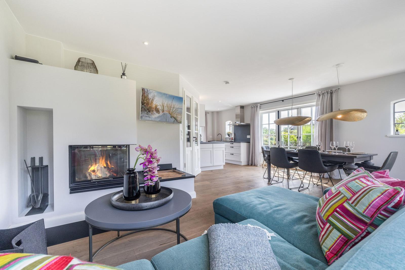 Wohnbereich mit Kamin, Sofa und Essbereich mit Tisch und Stühlen.
