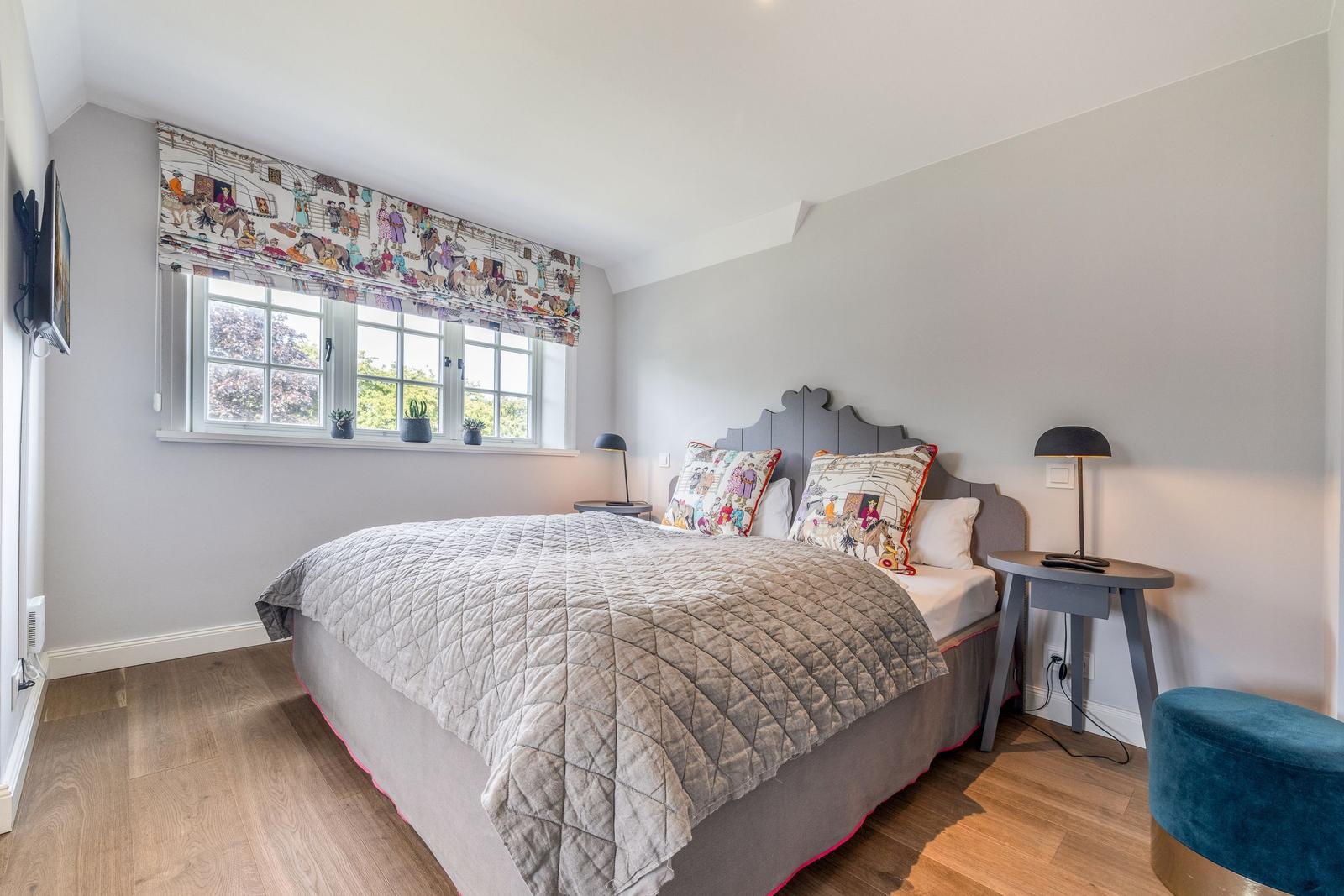 Schlafzimmer mit Bett, Fenster, Nachttisch und Stuhl.