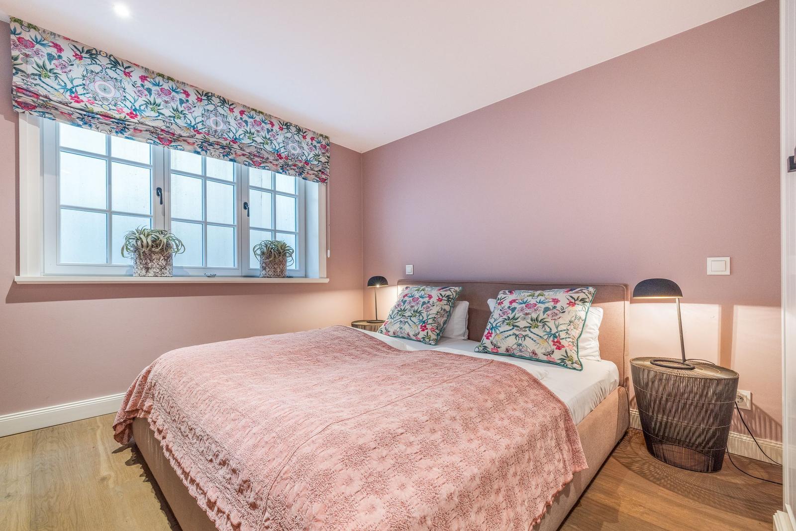Schlafzimmer mit Bett, Fenster und zwei Nachttischen.