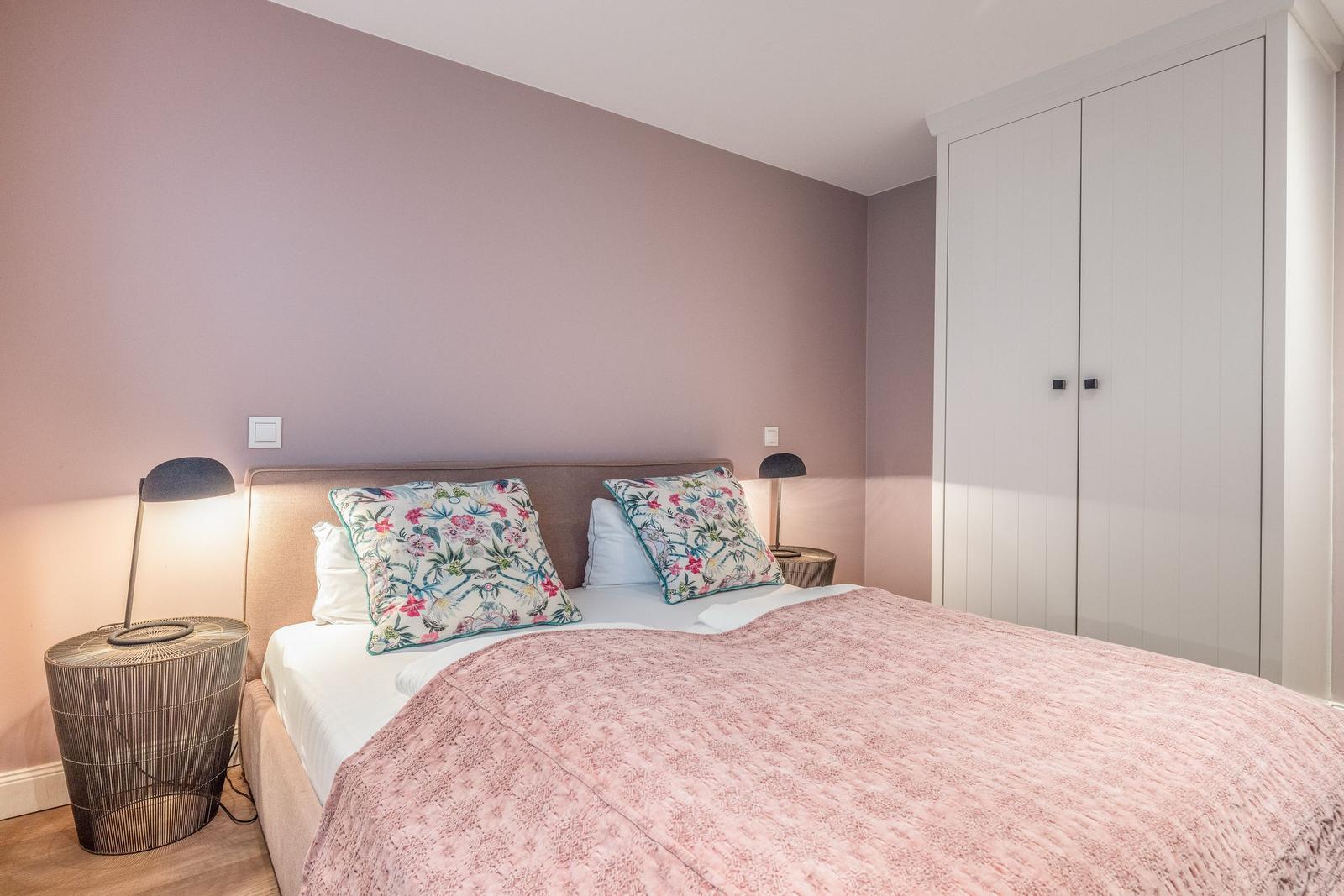 Schlafzimmer mit Bett, Kissen, Nachttisch und Kleiderschrank.
