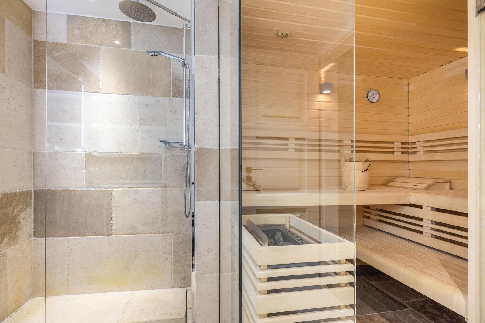 Dusche mit Steinwand und Sauna mit Holzbank und Ofen
