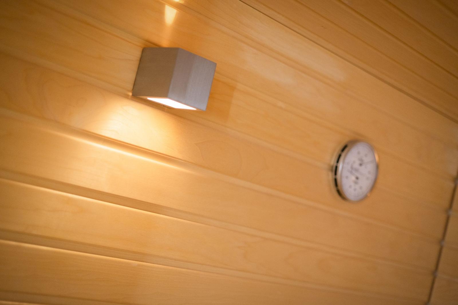 Wand mit Holzverkleidung, eingebaute Lampe und Thermometer.