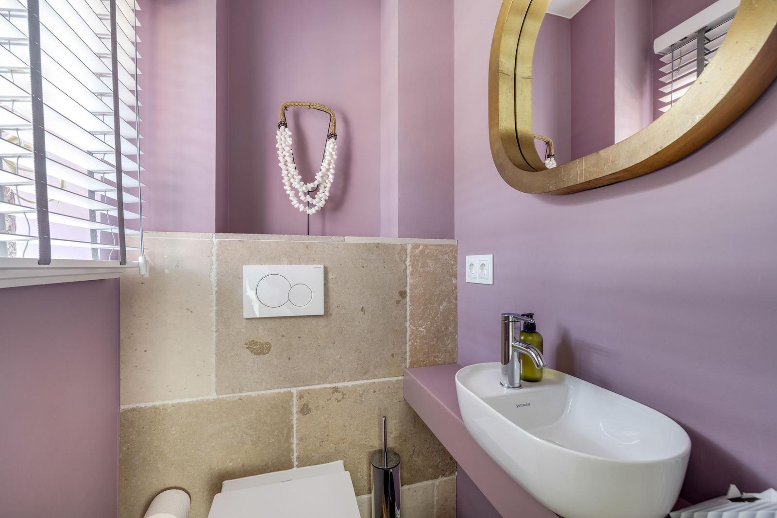 Badezimmer mit Lavendelwand, Waschbecken und runden Spiegel