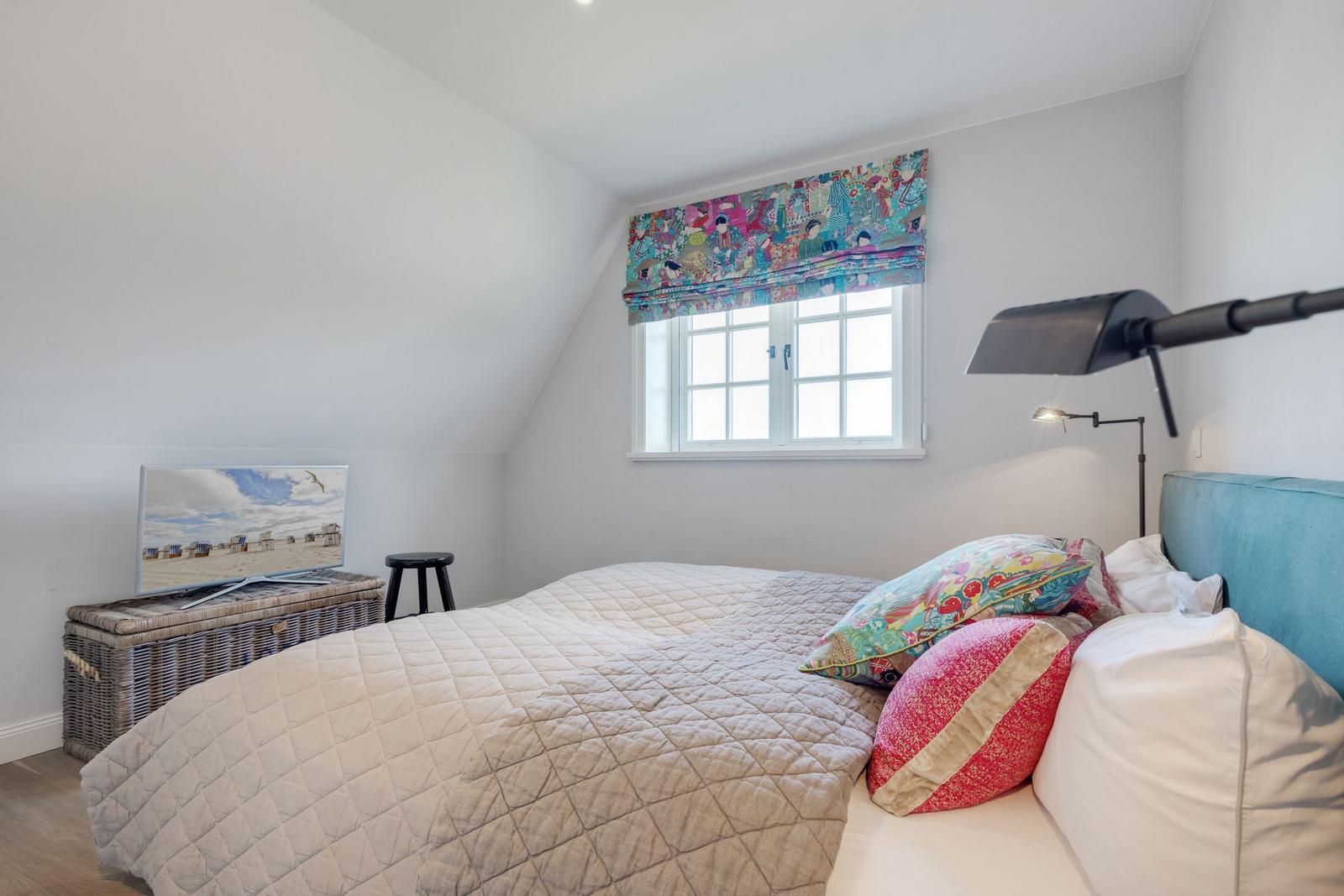 Schlafzimmer mit Bett, Fenster und Fernseher auf Kisten.