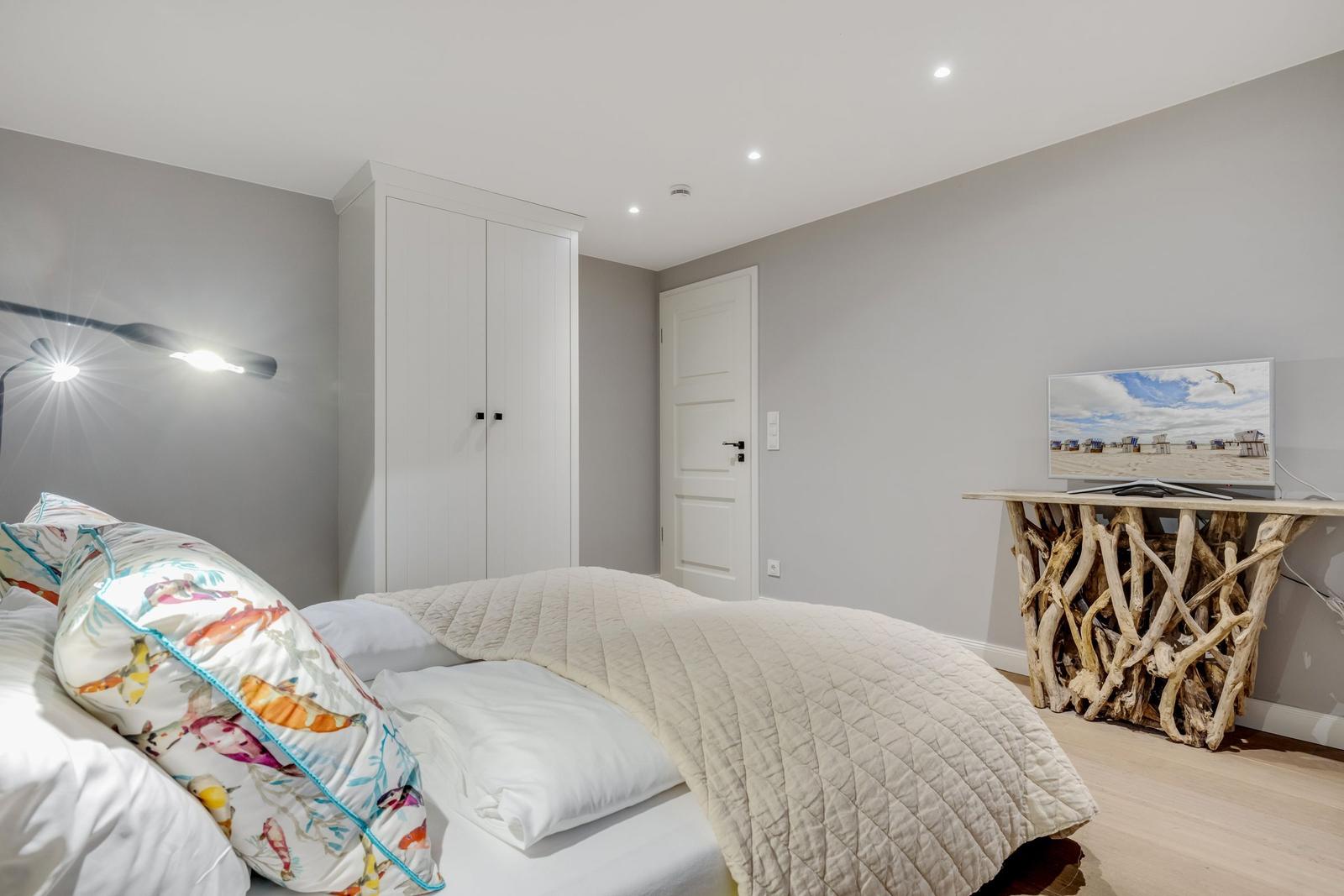 Schlafzimmer mit Bett, Kleiderschrank und TV auf rustikalem Tisch.