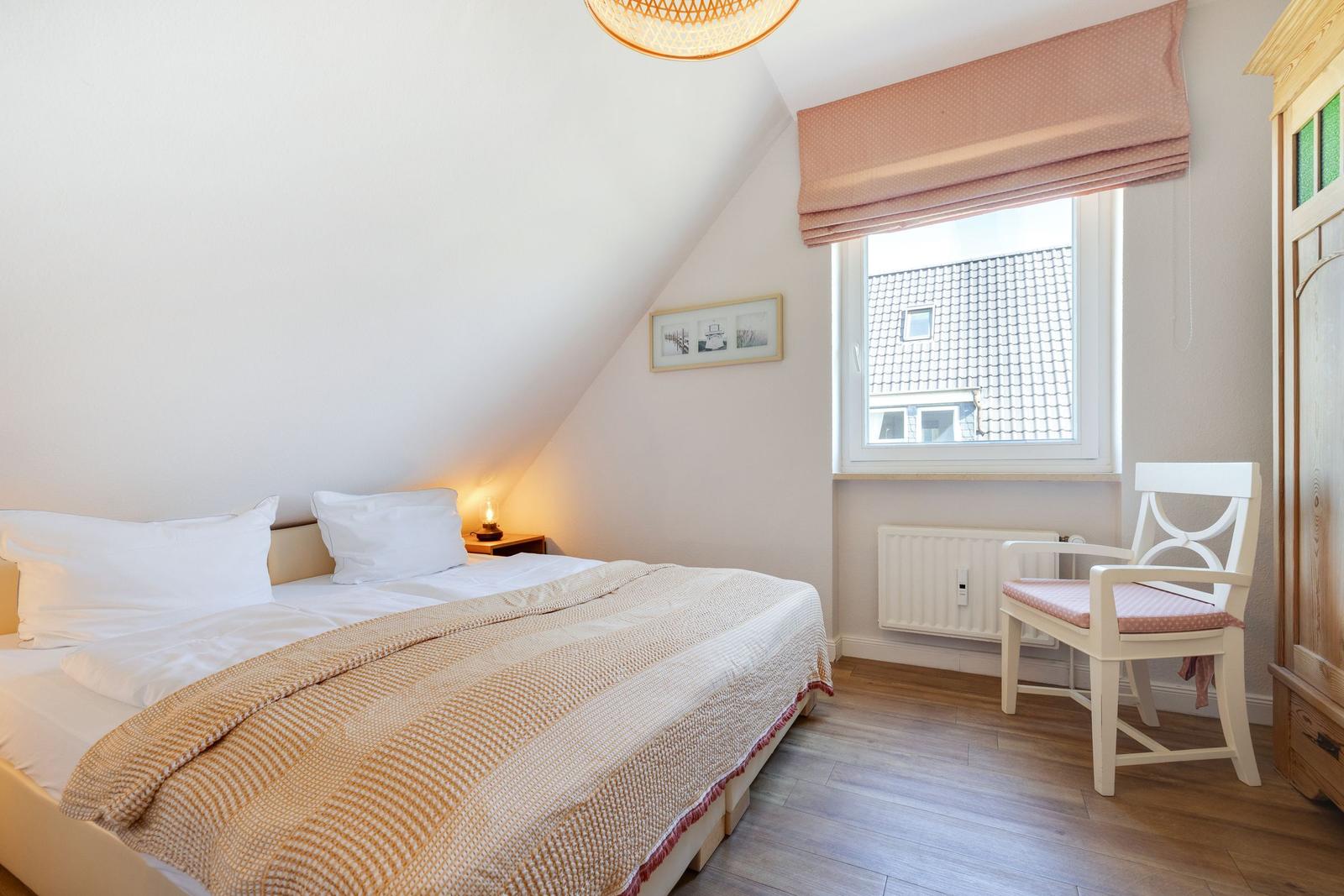 Bedroom with double bed, window, and chair.