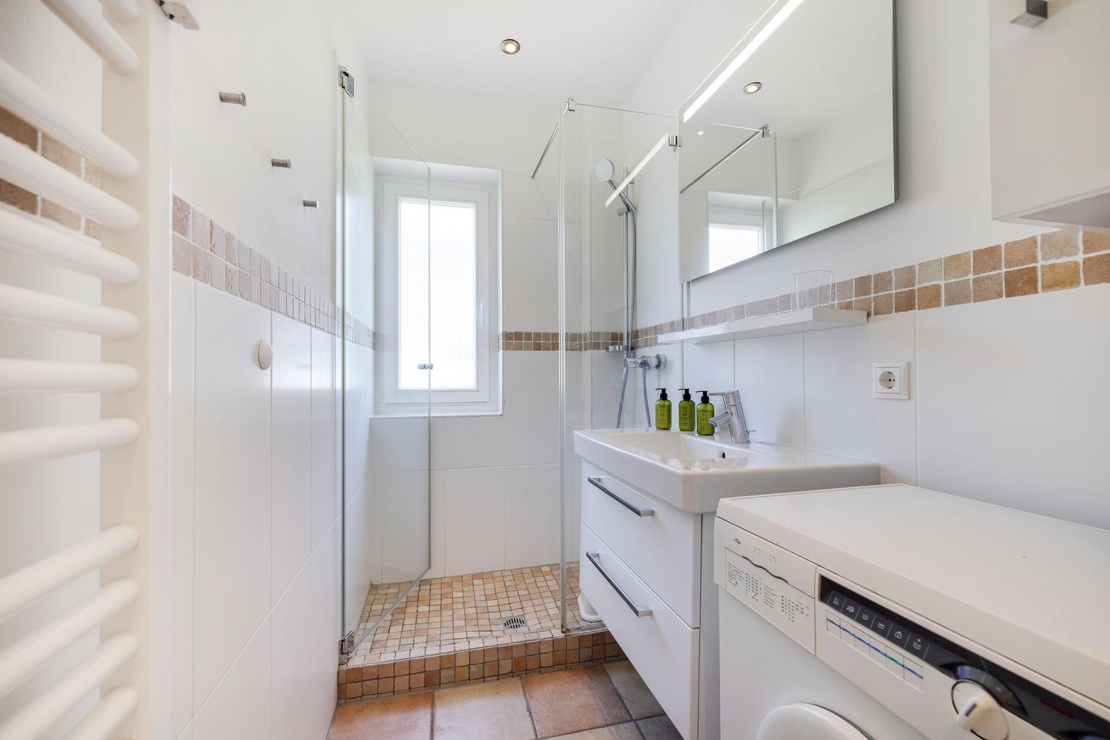 Bathroom with shower, sink, and washing machine.