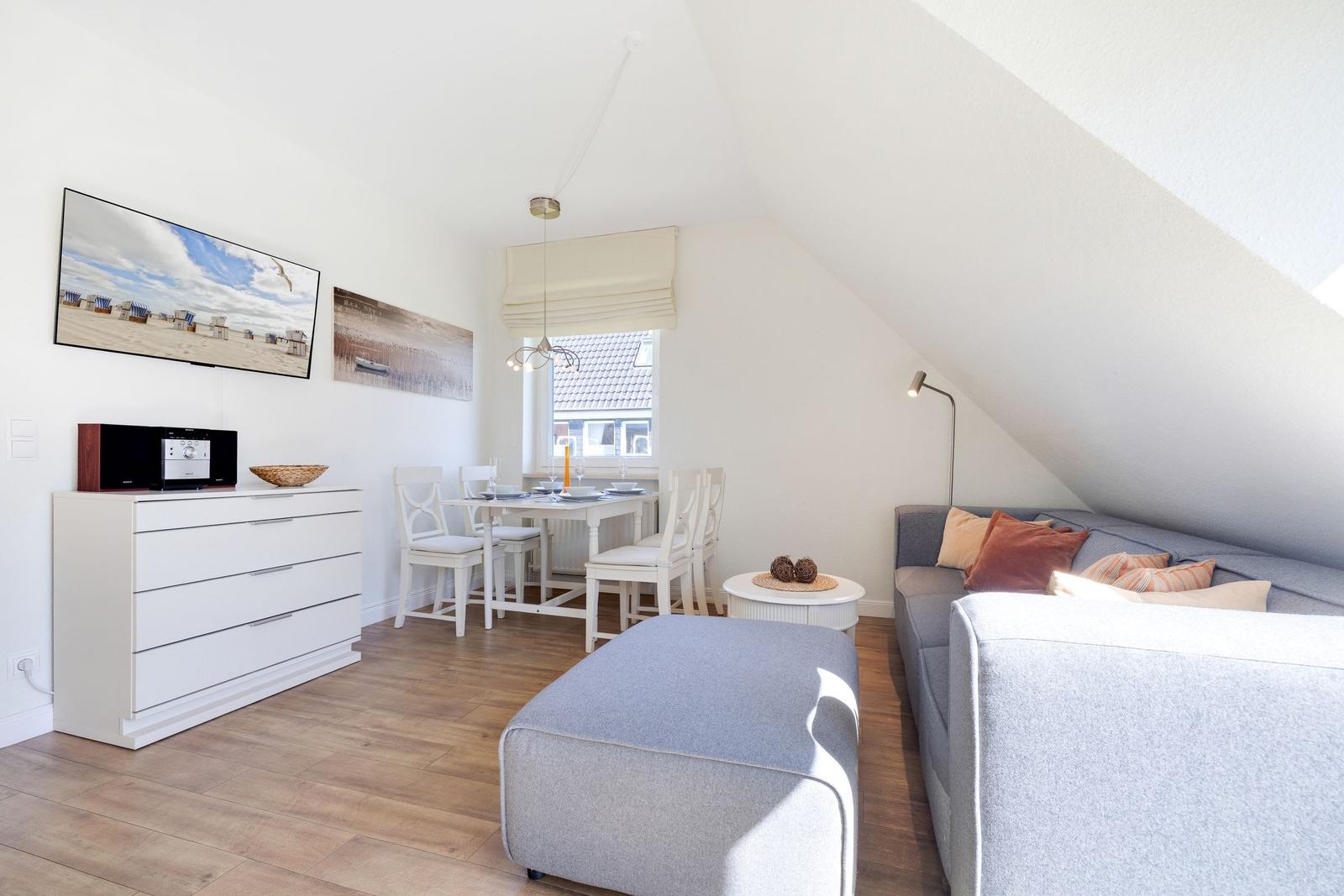 Living and dining area with sofa, dining table, and TV on the wall.