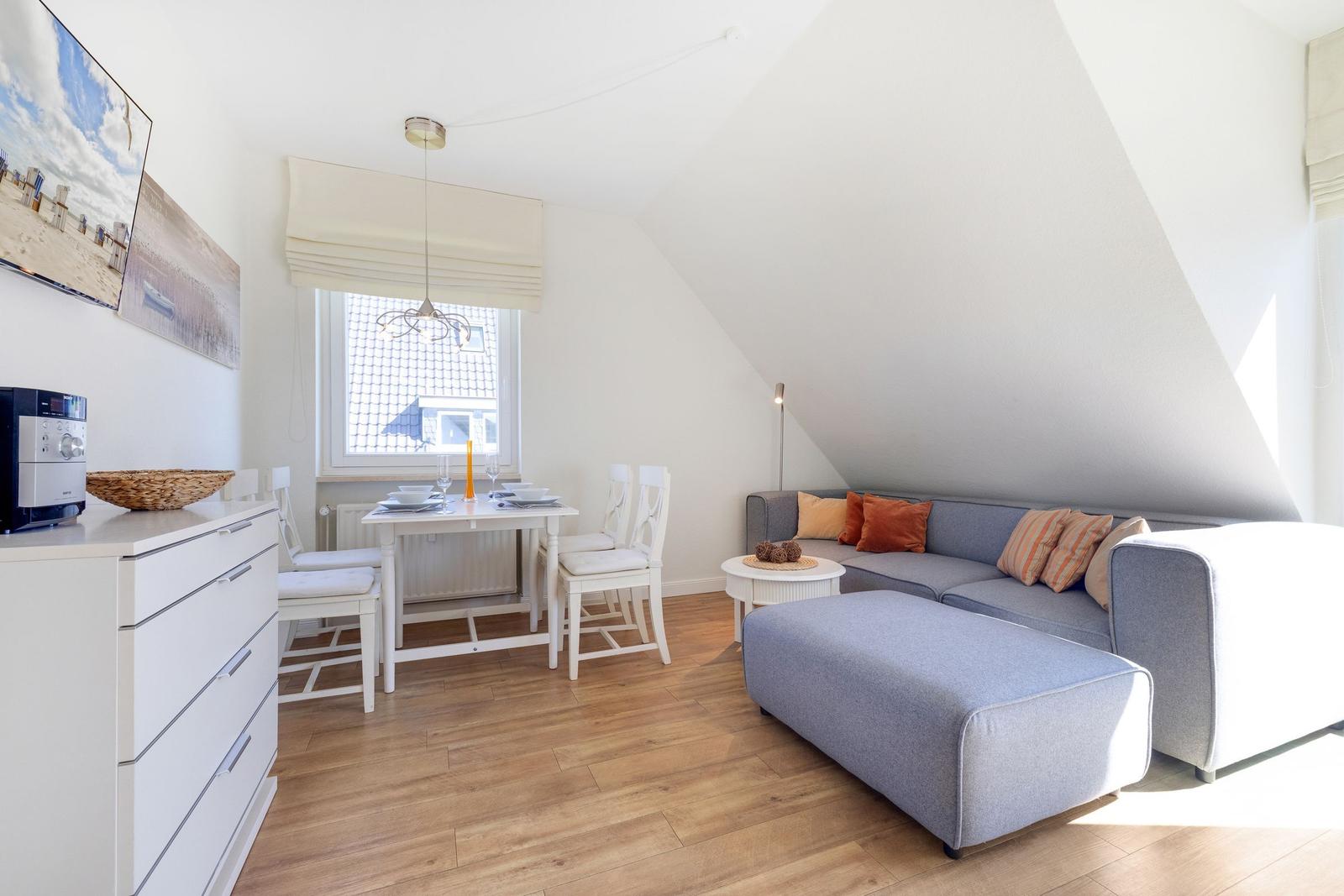 Living and dining area with sofa, table, chairs, and window.