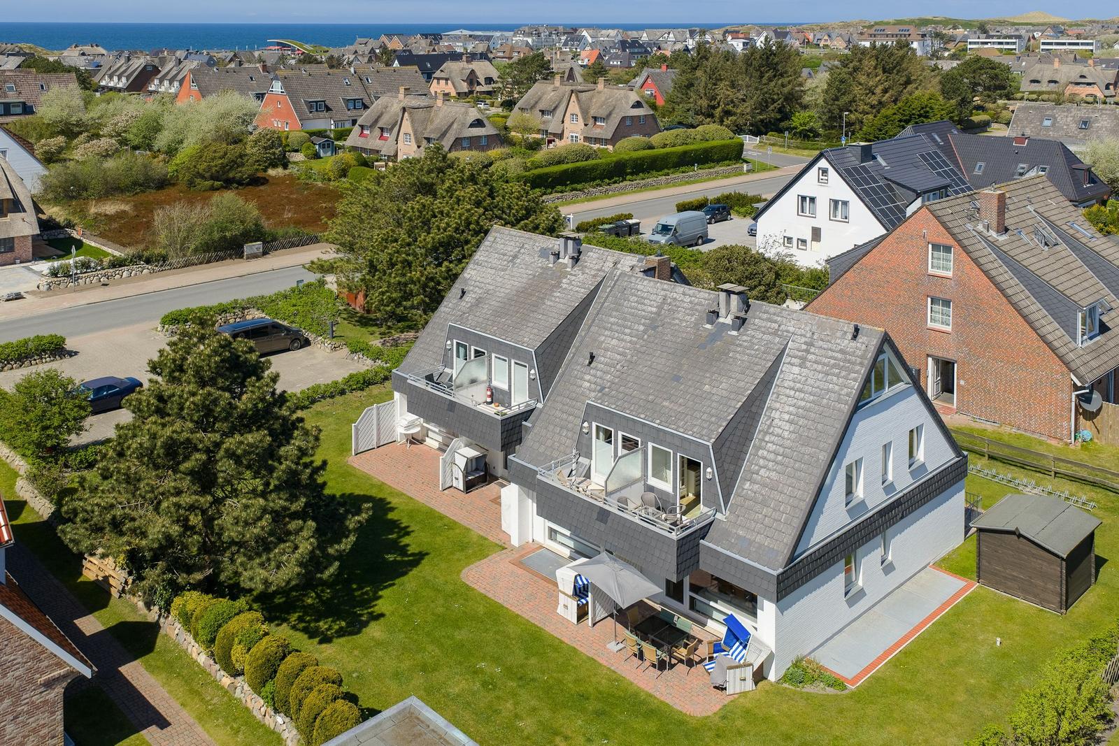 Modern house with balcony, terrace, and garden. View of the coast and neighborhood.