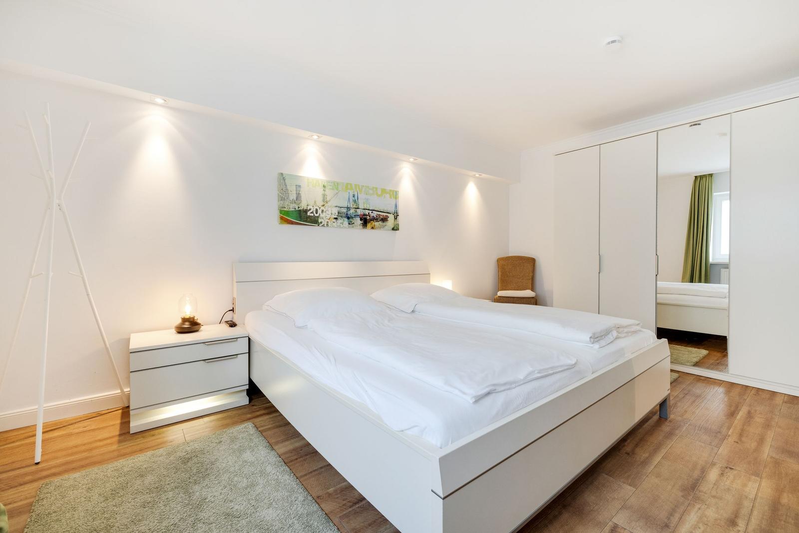 Bedroom with white bed, nightstand, and wardrobe.