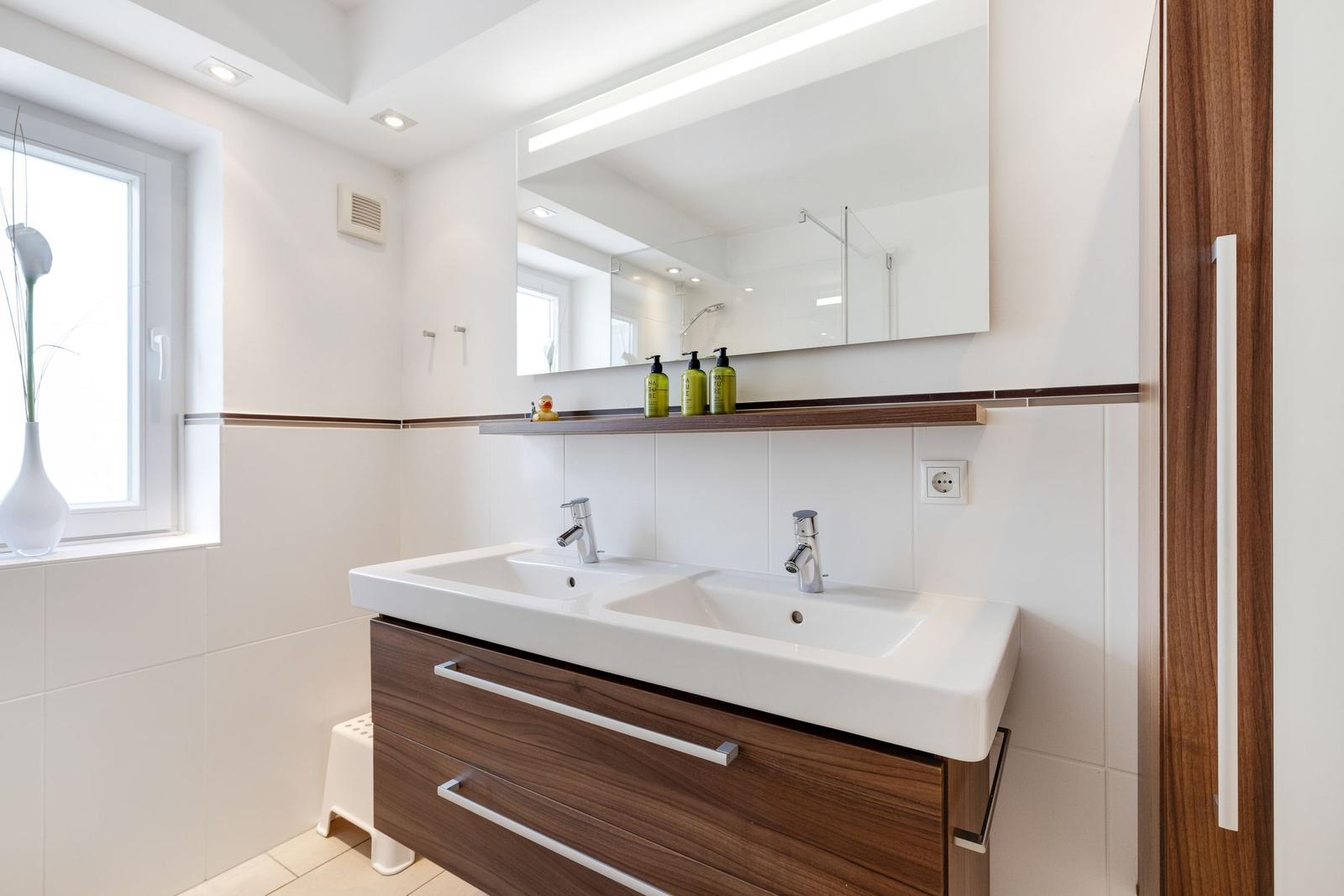Bathroom with double sink, mirror cabinet, and window
