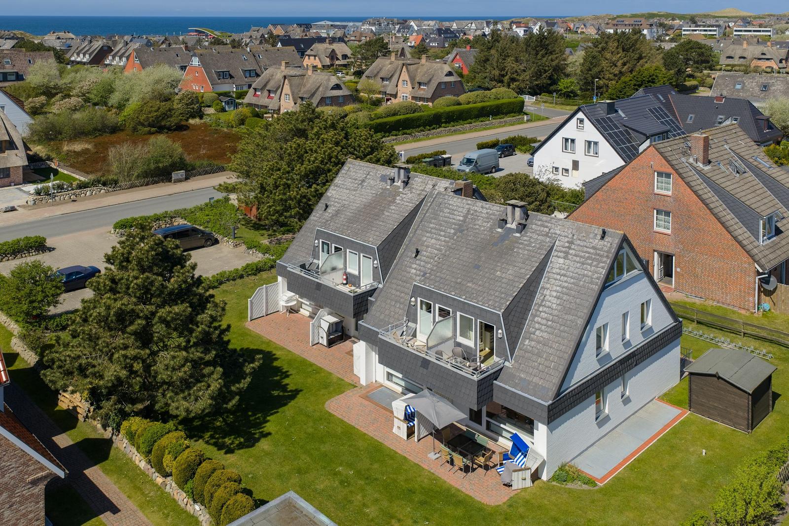 Modern house with balcony, terrace, and garden. View of the coast and neighborhood.