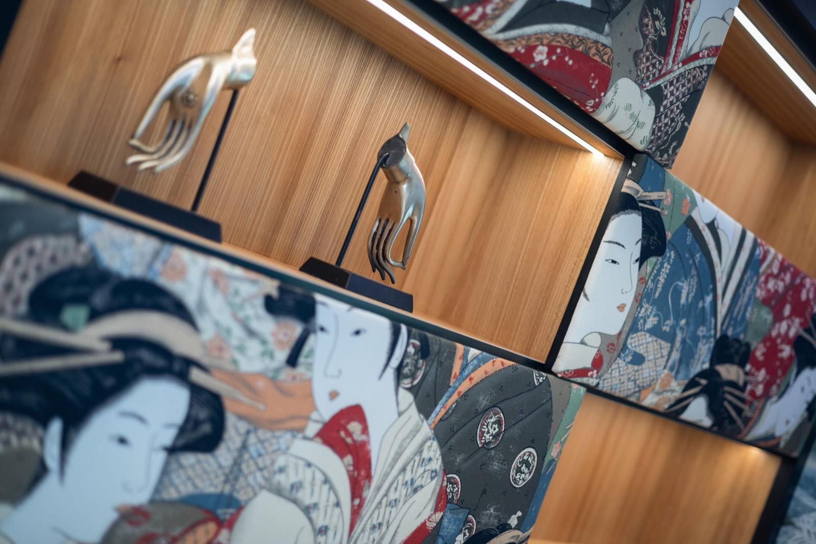 Wand mit japanischen Kunstwerken und Metallskulpturen von Händen.