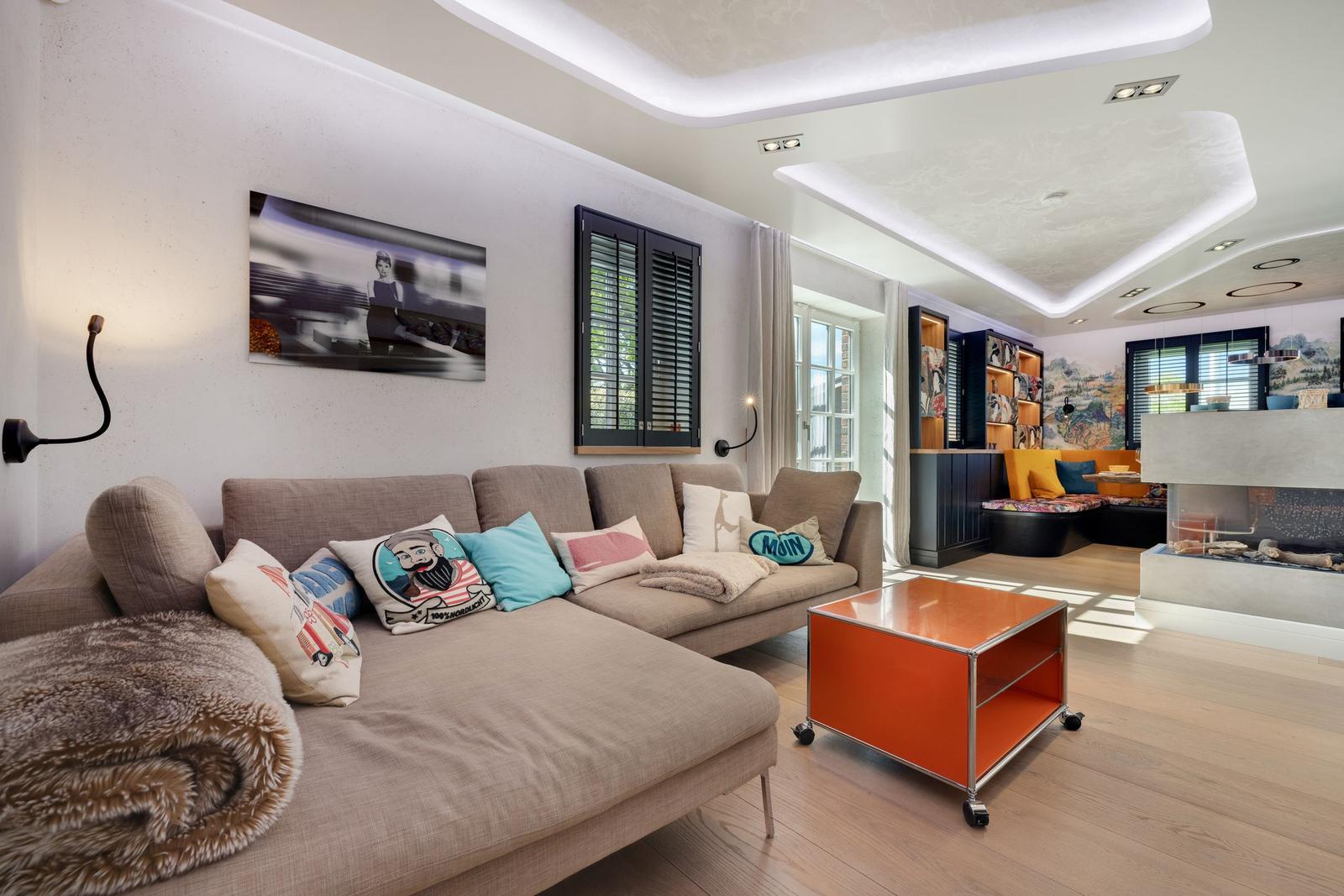 Wohnzimmer mit Sofa, orangefarbenem Tisch und Kamin