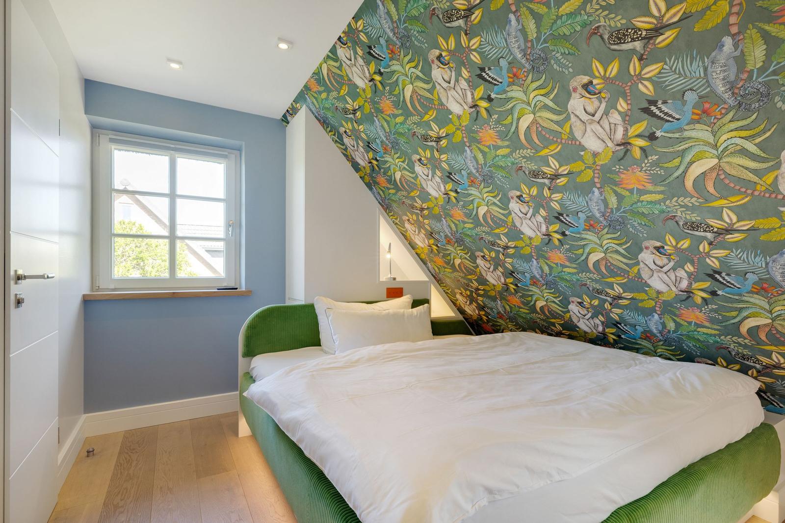 Schlafzimmer mit grünem Bett und buntem Tapetenwand