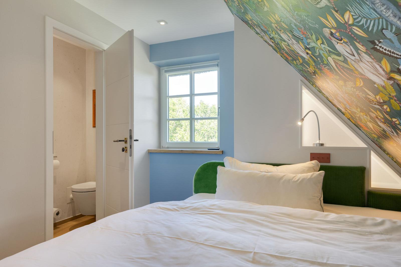 Schlafzimmer mit Bett, Fenster und Badezimmer. Decke mit Tiermotiven.