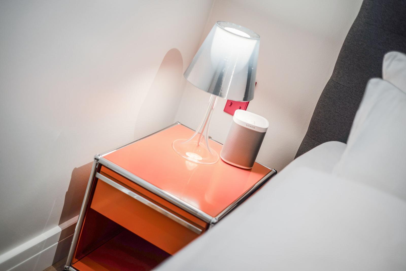 Schlafzimmer mit Nachttisch, Lampe und Lautsprecher