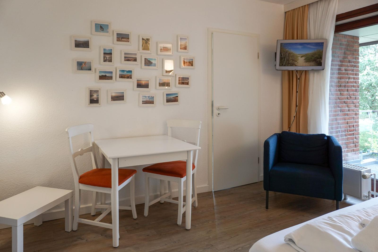 Ein Zimmer mit Tisch, Stühlen, Sofa und Fernseher an der Wand.