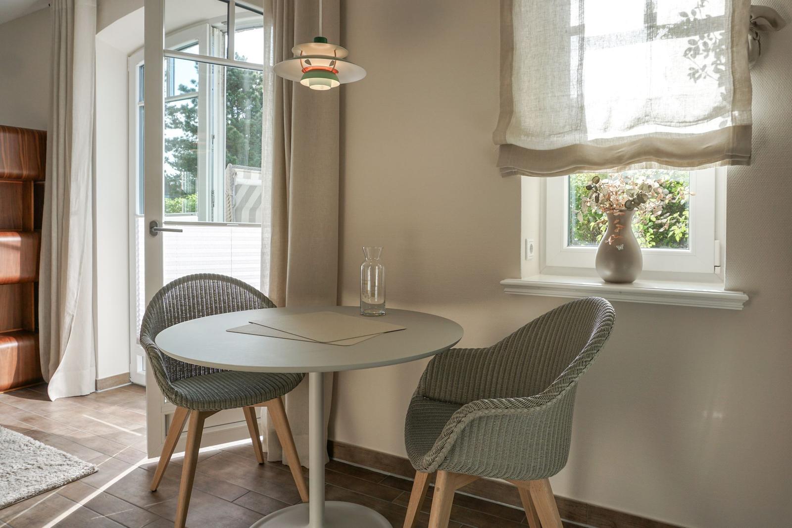 Round table with two chairs, window and lamp in the room.