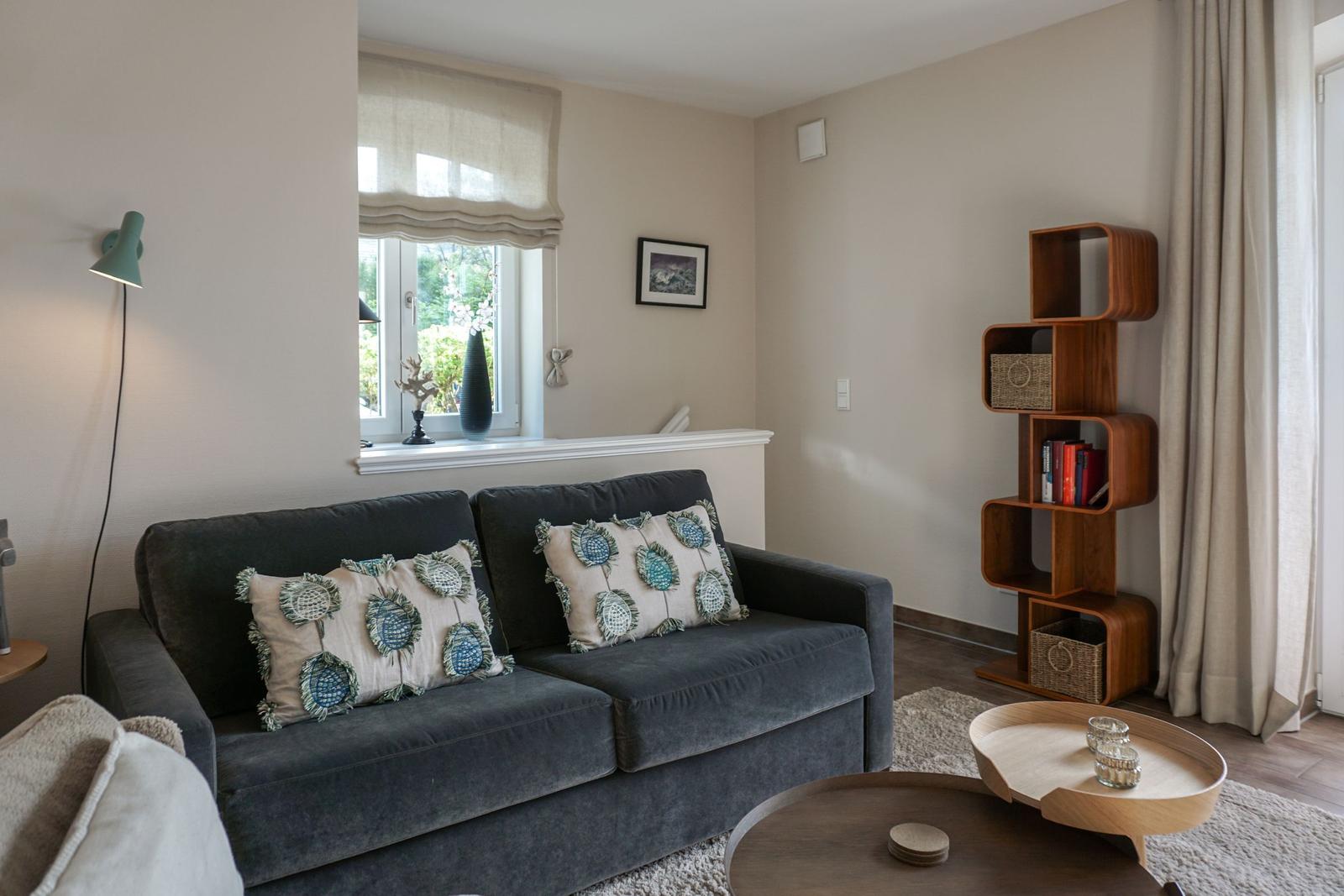 Living room with gray sofa, decorative cushions, and wooden bookshelf.