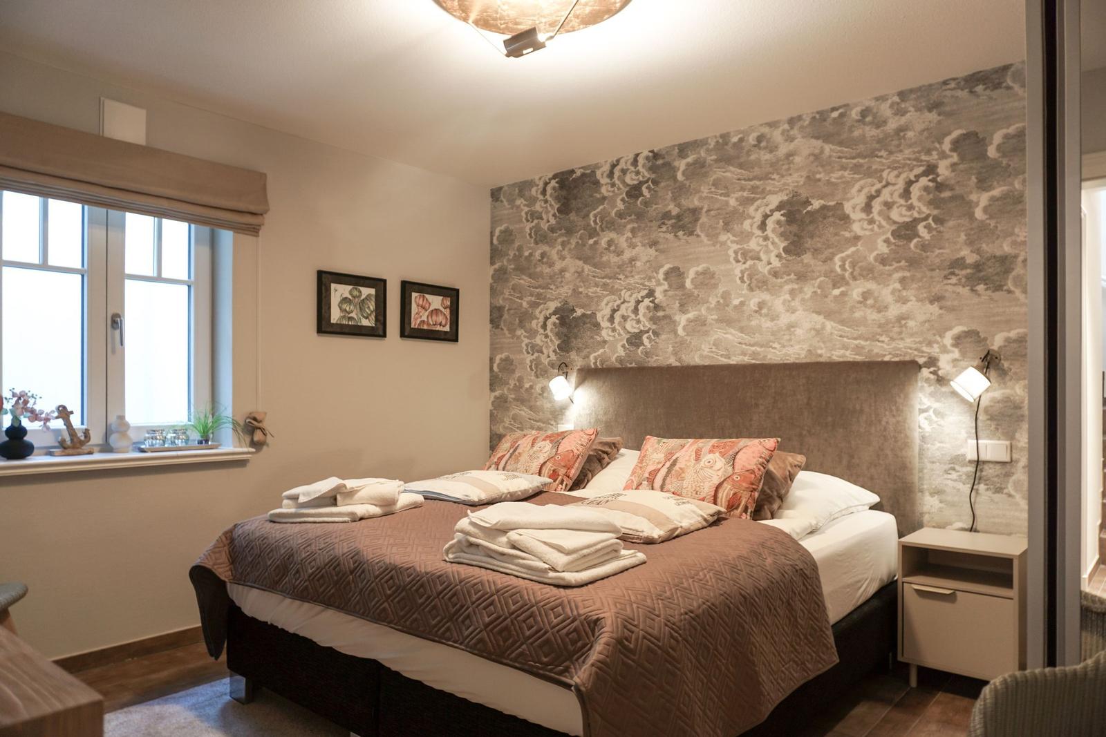 Bedroom with bed, headboard, and wall covering with wave pattern.