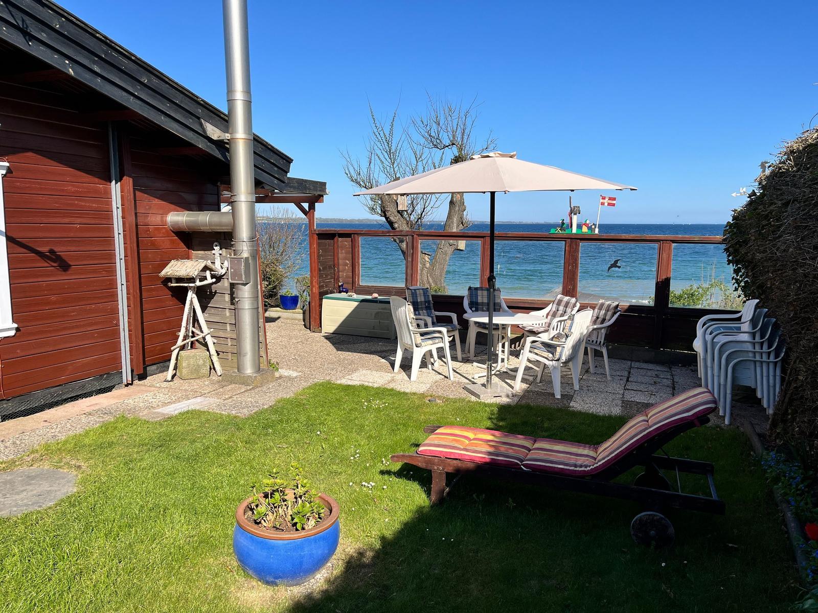 Terrasse mit Sitzgruppe, Sonnenschirm und Blick aufs Meer.
