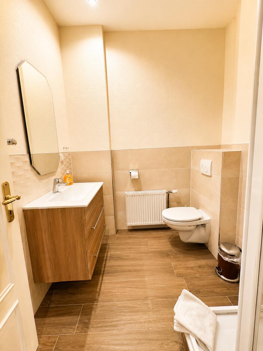 Badezimmer mit Waschbecken, Spiegel, Toilette und Heizkörper.