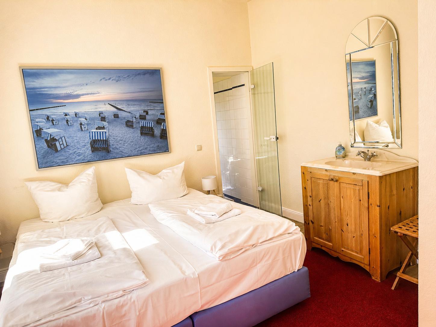 Schlafzimmer mit Doppelbett, Bad mit Dusche und Holzwaschbecken.
