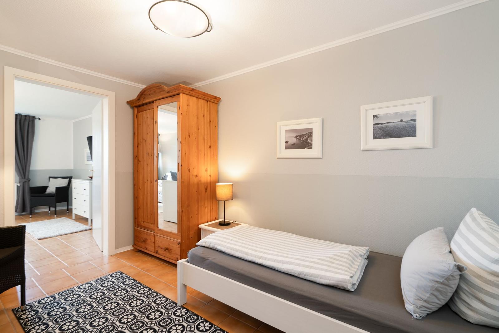 Bedroom with bed, wardrobe, and pictures on the wall.
