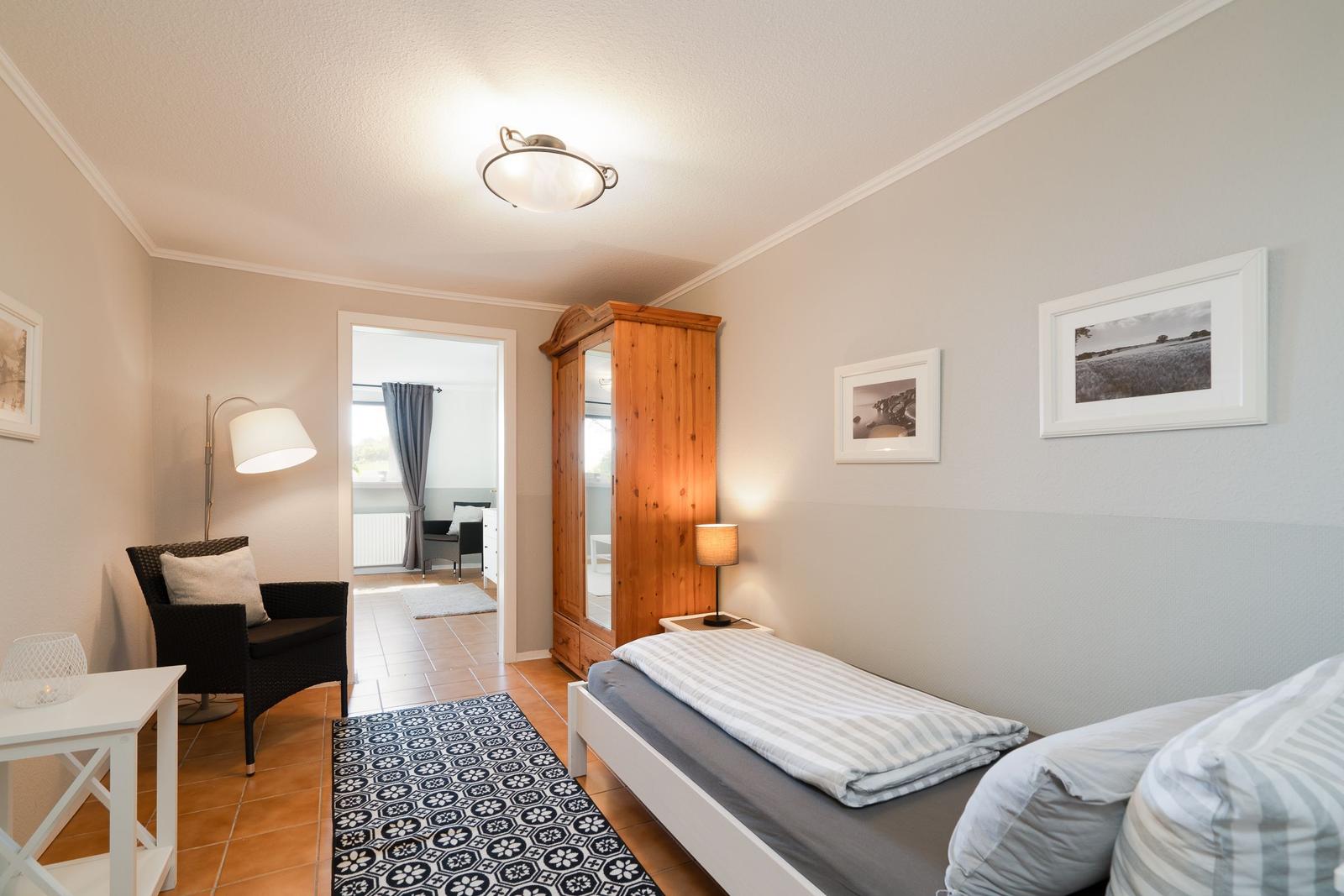 Bedroom with bed, wardrobe, and seating. Passage to living area.