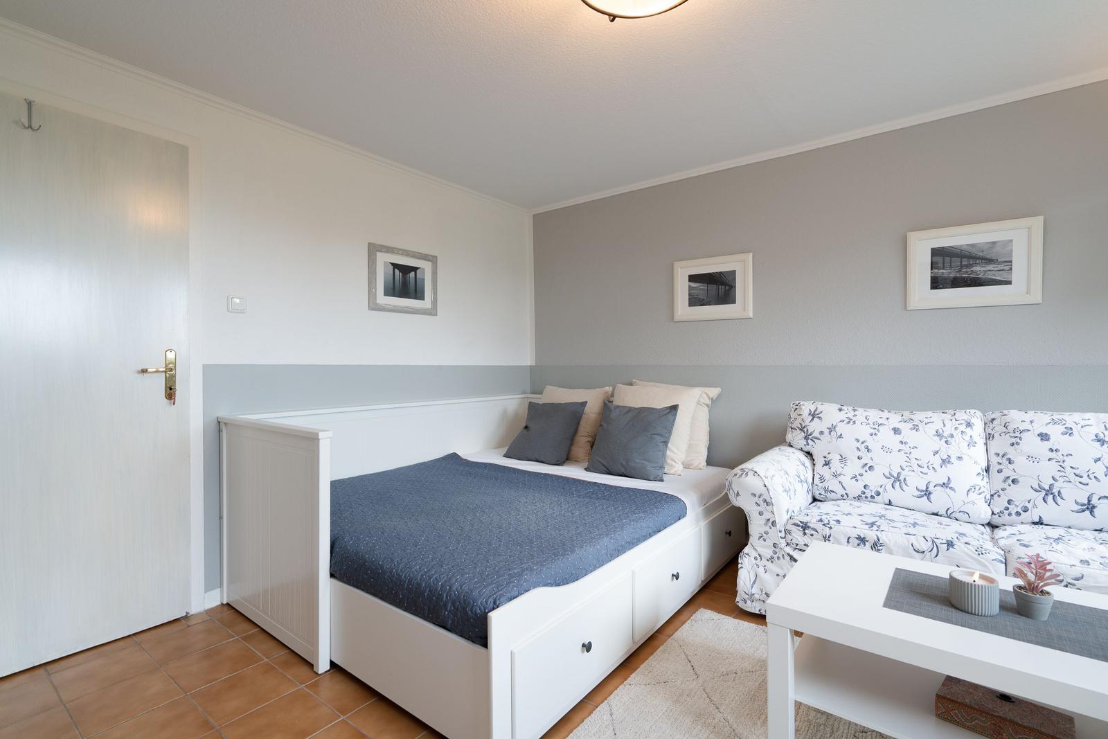 Bedroom with bed, sofa, and table. Walls painted in two colors.